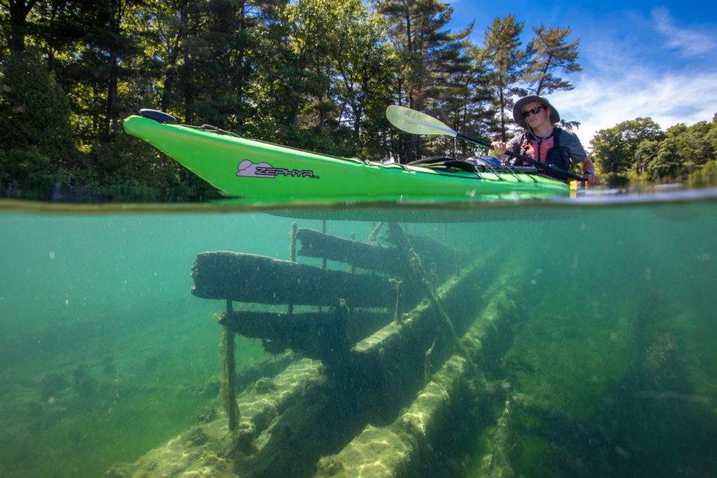 A kayaker floats above a submerged shipwreck