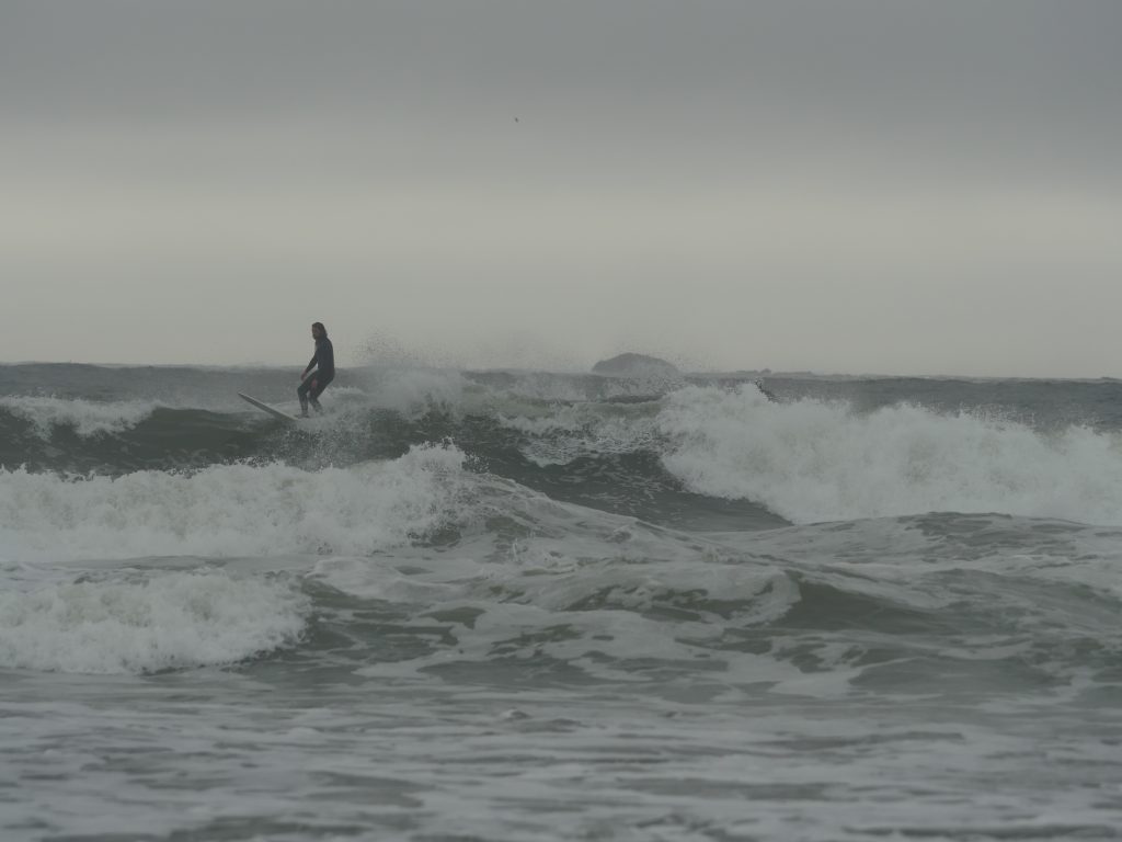 A surfer rides the waves on a grey day