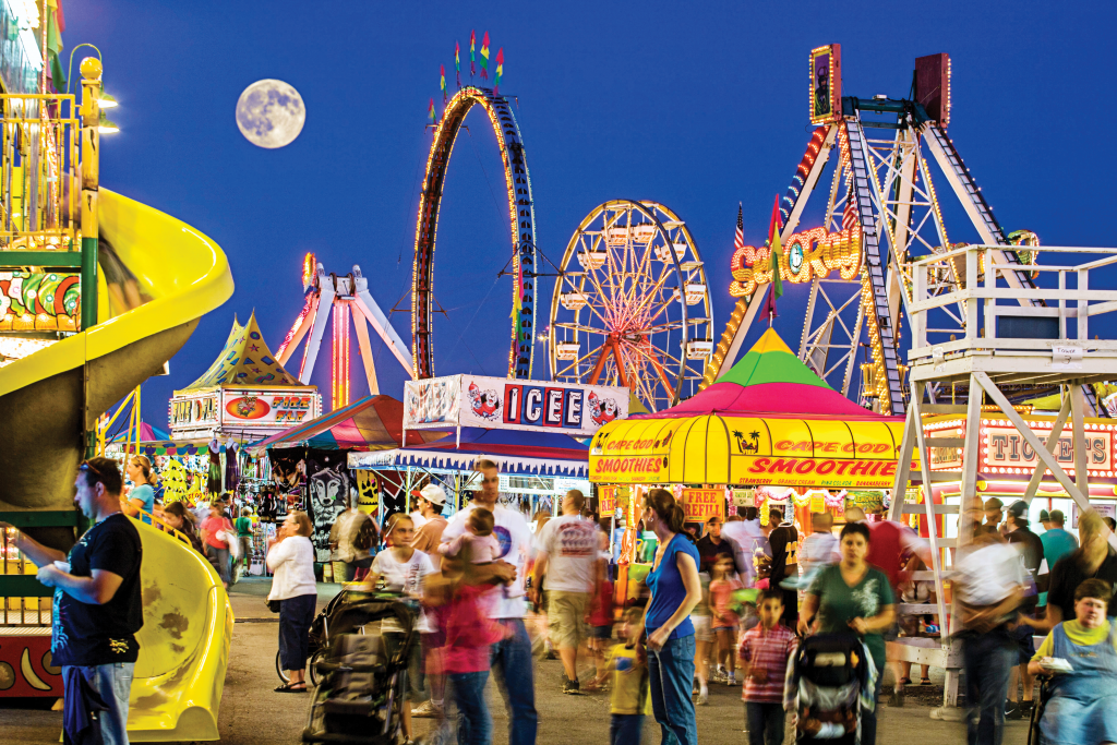 Crowds enjoy a brightly lit fairground at night