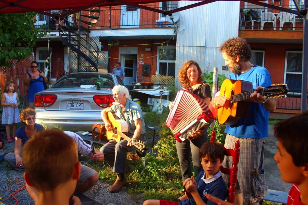 A group of musicians play perform for their neighbours in a green alley